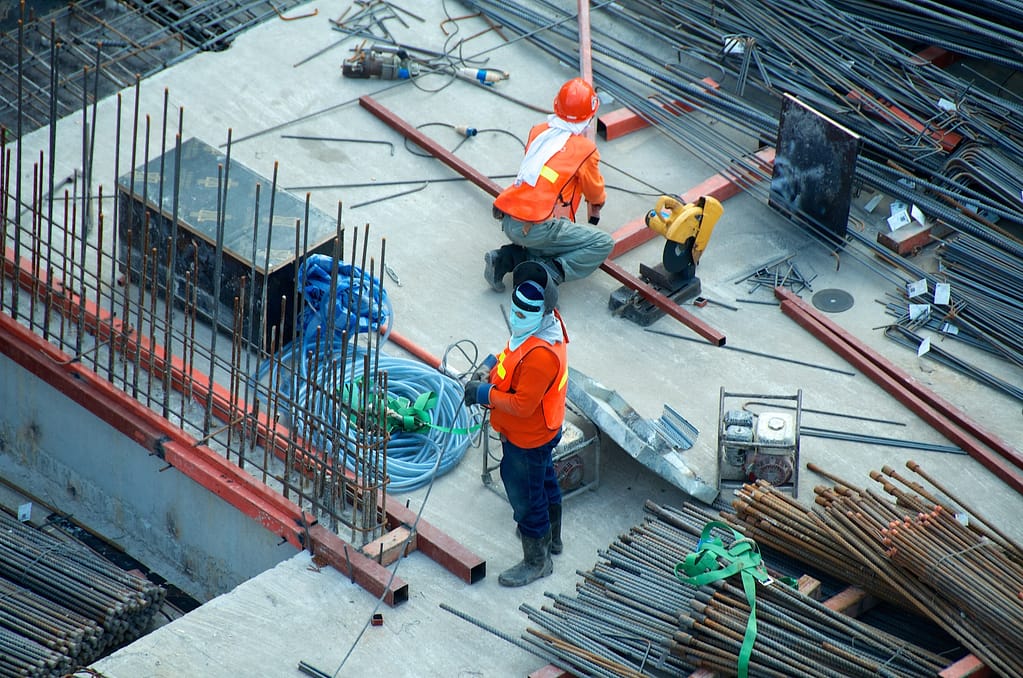 deux ouvriers sur un chantier entourés de matériaux de construction