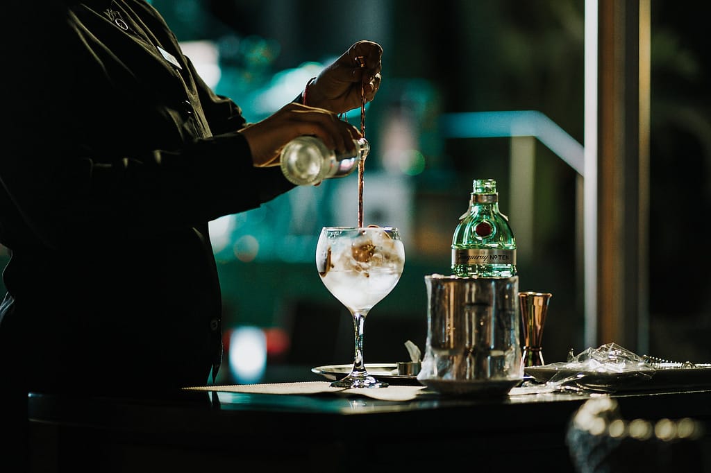 barman qui prépare un cocktail avec du gin