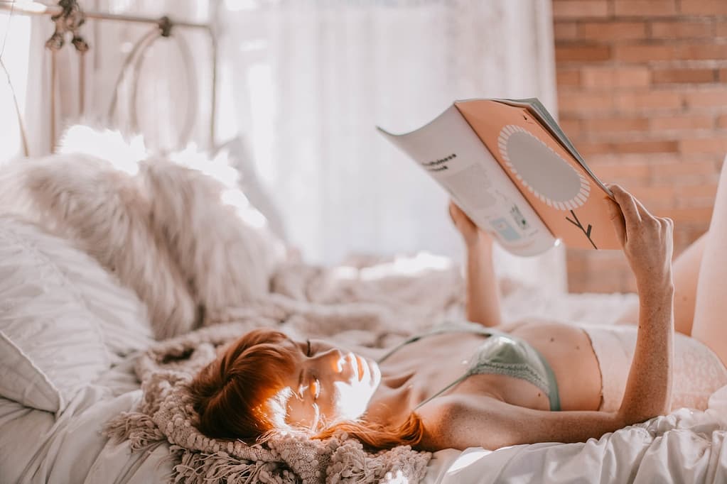 femme en lingerie qui lit un livre dans un lit
