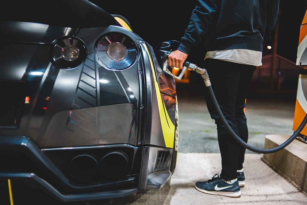 homme qui fait le plein d'essence de sa voiture de sport