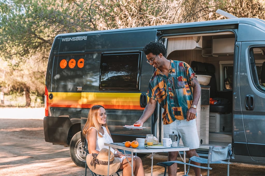 deux personnes qui mangent devant un van dans la nature