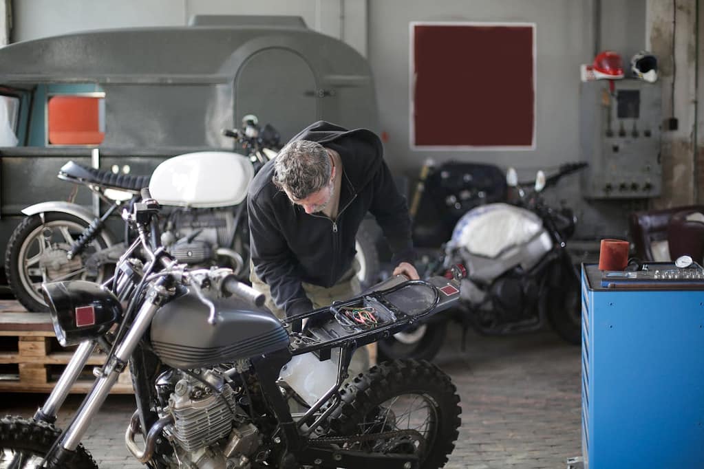 mécanicien qui répare une moto dans un garage