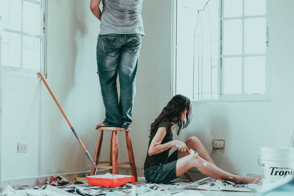 un homme et une femme en train de bricoler dans une pièce de la maison