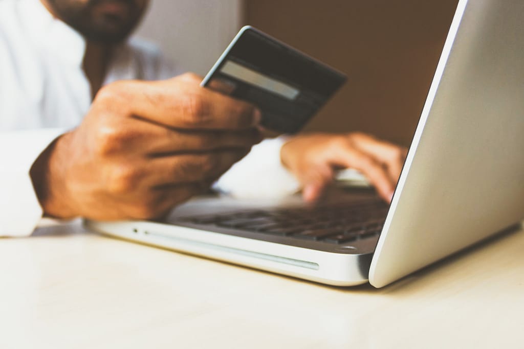 Consommateur dace à son ordinateur lisant sa carte de crédit pour payer en ligne
