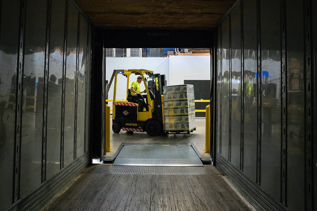 conducteur dans un chariot élévateur qui déplace un chargement dans un camion de transport