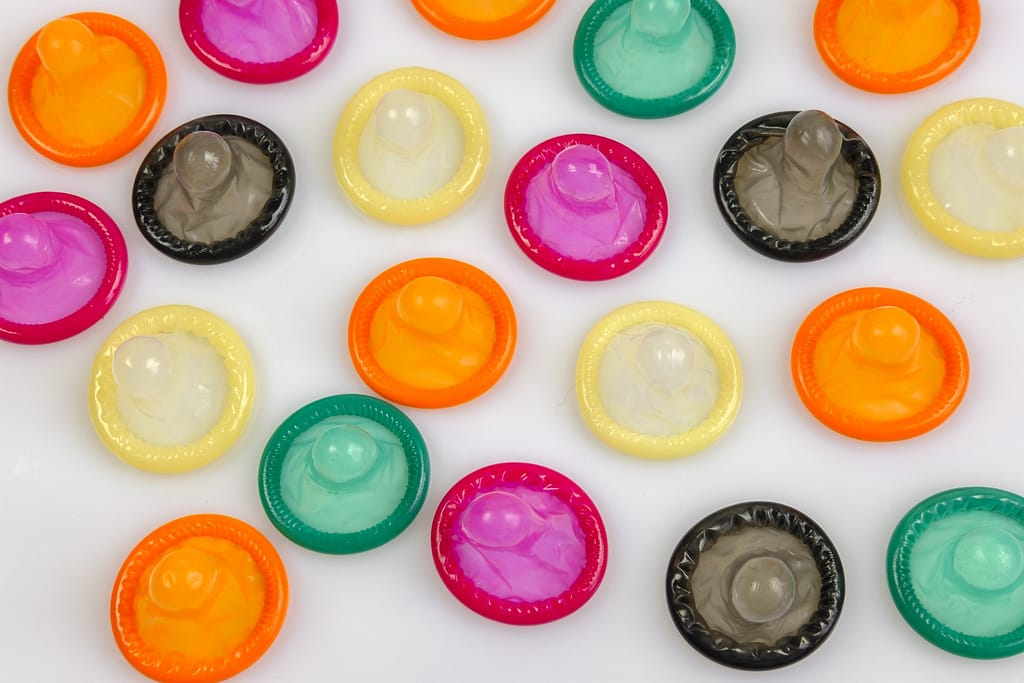 plusieurs préservatifs de différentes couleurs et de différents types posés les uns à côté des autres