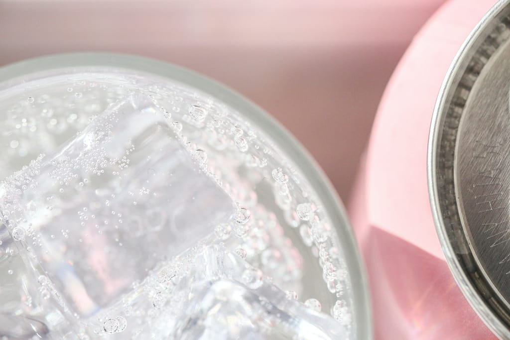 eau gazeuse dans un verre à côté d'une canette