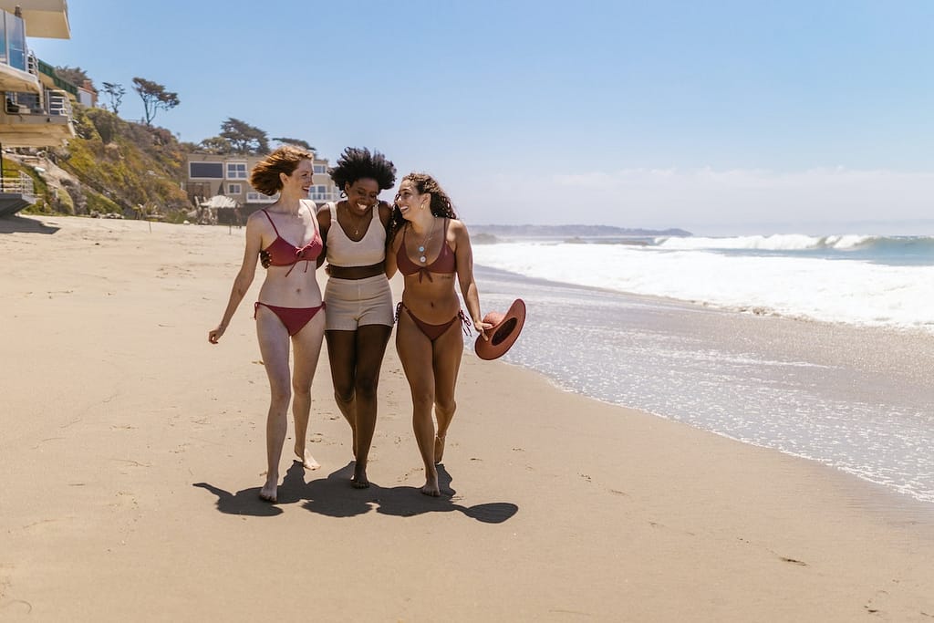 trois femmes qui déambulent en maillot de bain sur une plage