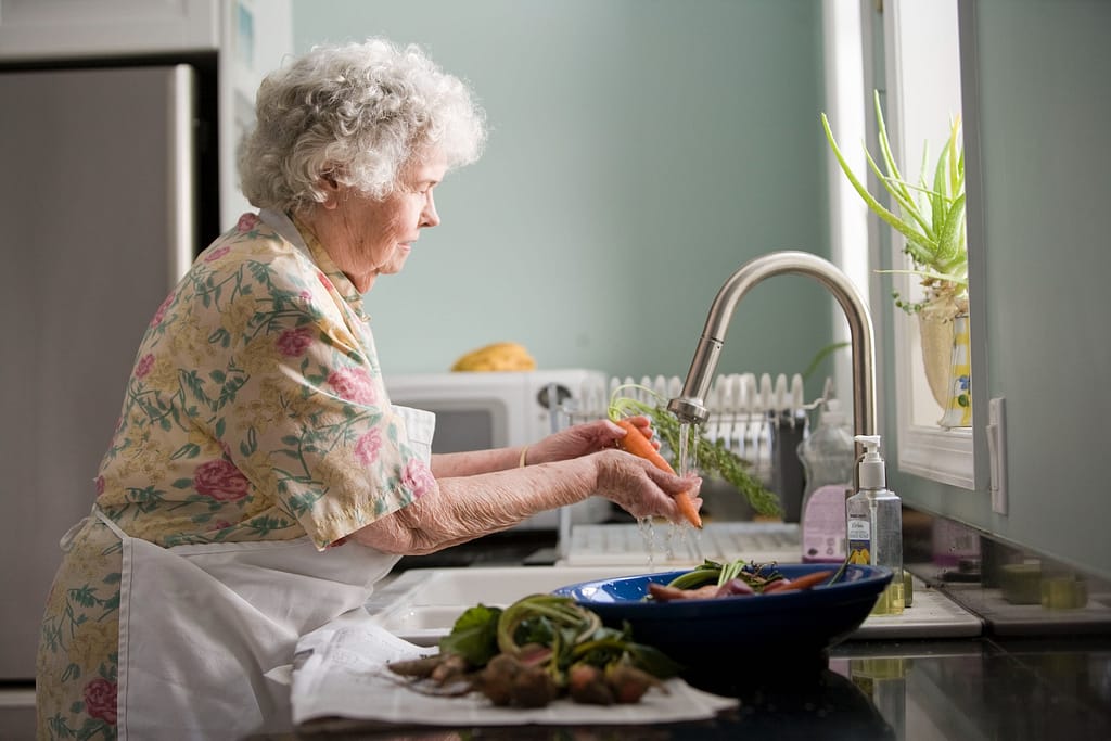 personne âgée qui fait la cuisine dans une résidence senior