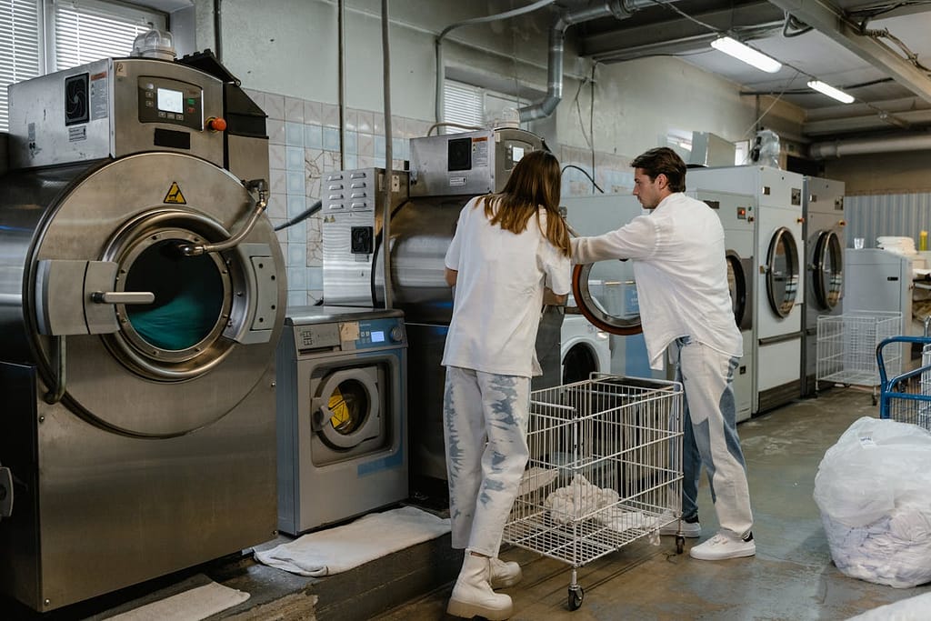 salariés qui font fonctionner une machine à laver dans un pressing