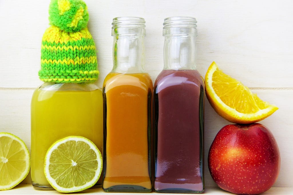 plusieurs types de jus de fruits avec des rondelles de citron et une pomme
