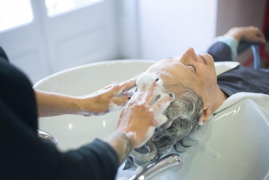 coiffeur qui fait un shampooing à une cliente