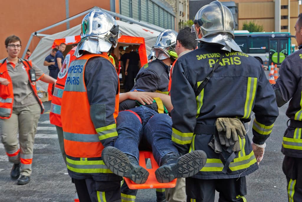 pompiers avec des vêtements ignifuges qui transportent un blessé