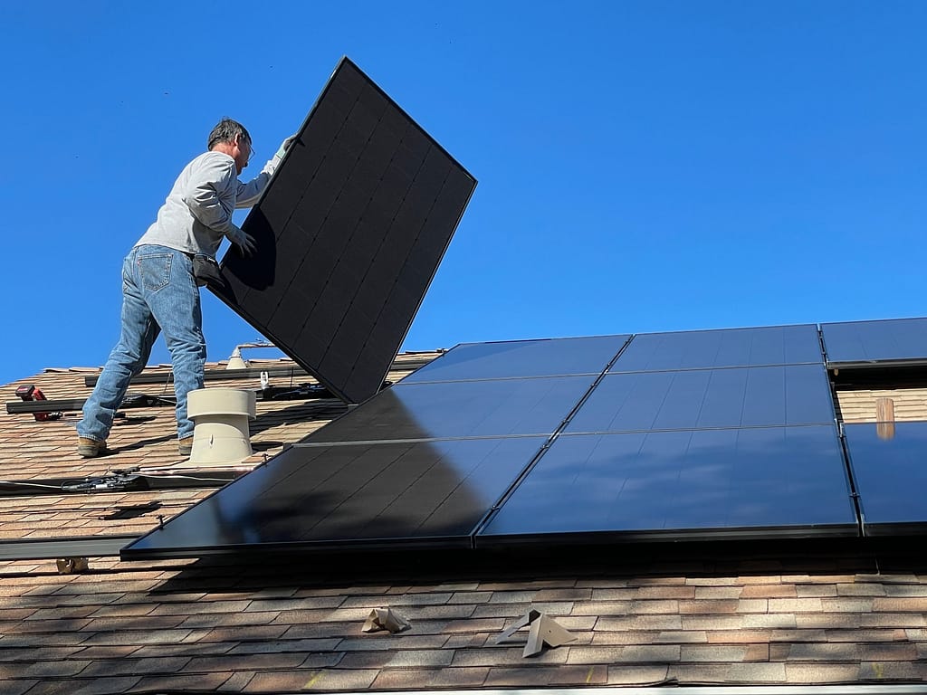 homme qui pose les panneaux solaires sur le toit d'un particulier