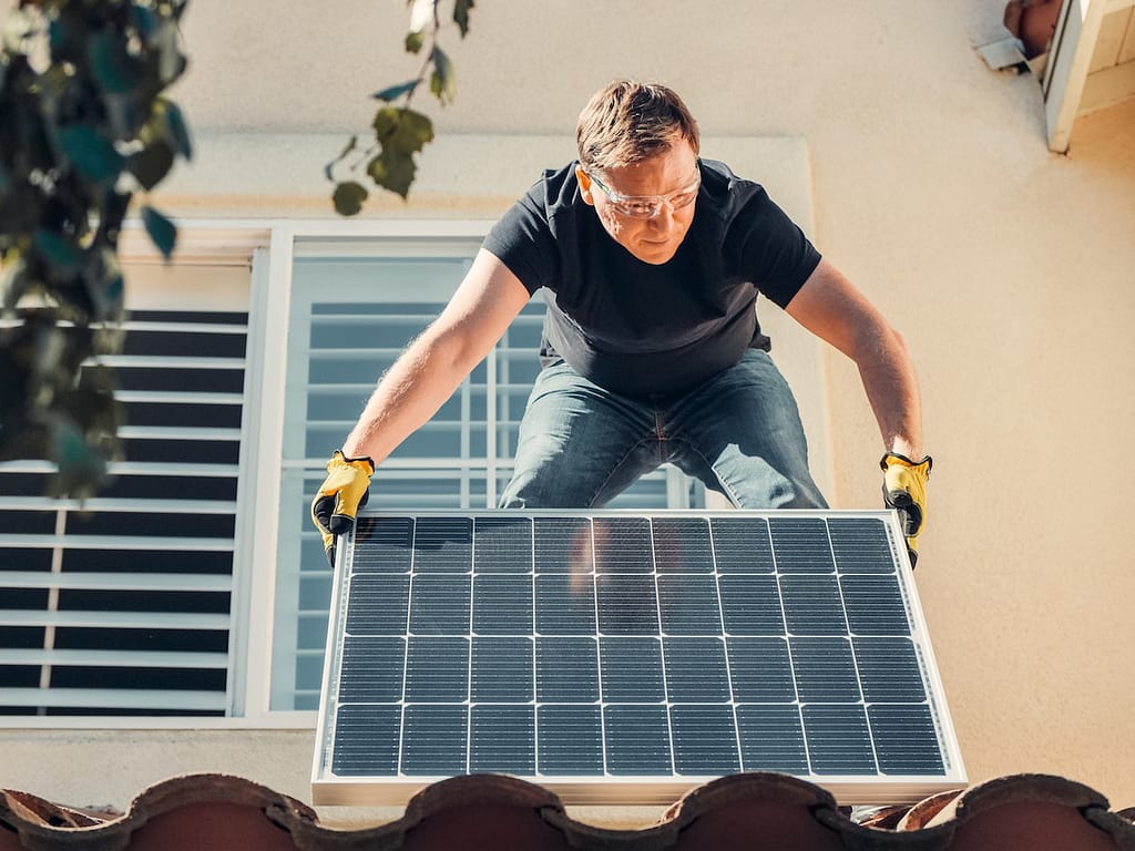 un homme qui installe un panneau solaire sur son toit