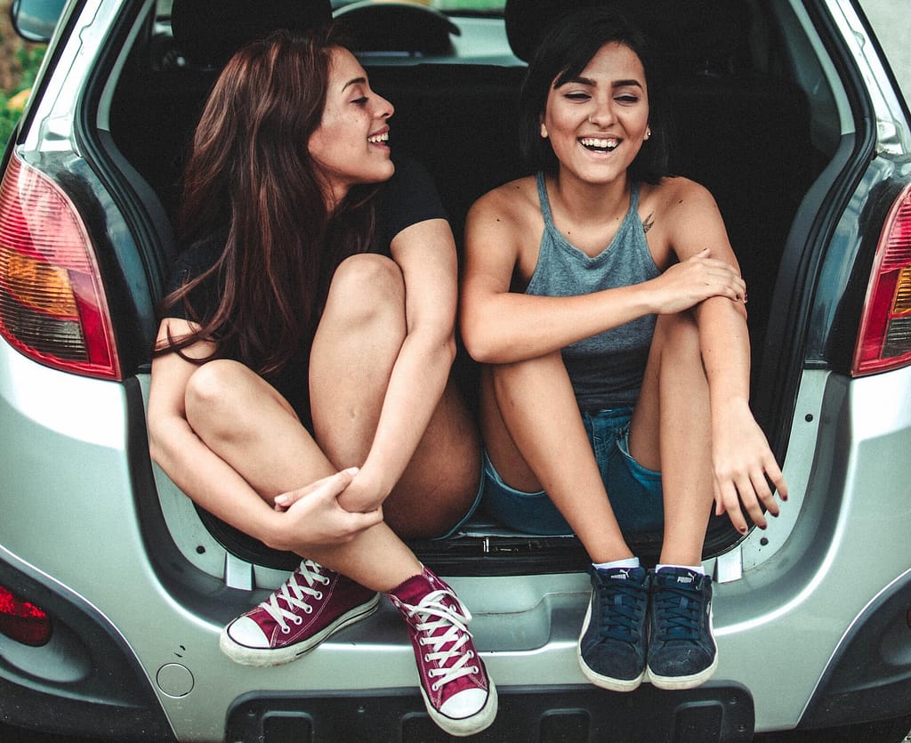 deux jeunes femmes en covoiturage assises dans le coffre d'une voiture