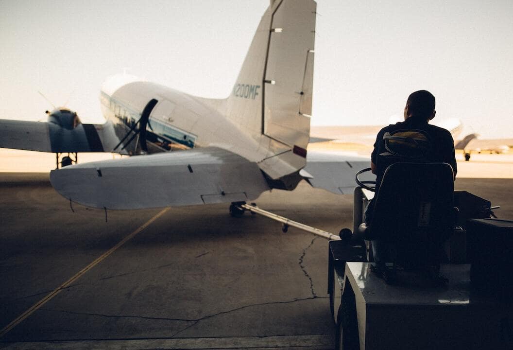 bagagiste qui se dirige vers un avion sur une piste d'atterrissage