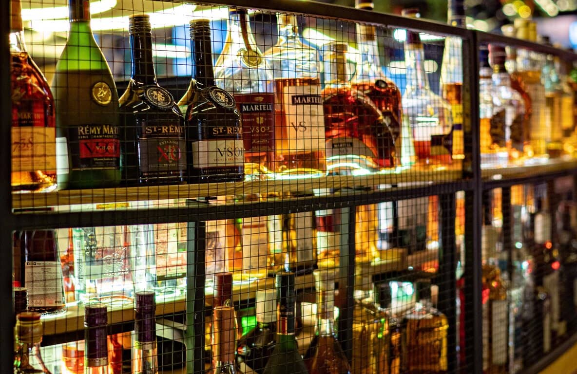 plusieurs bouteilles de Cognac de différentes marques sur une étagère dans un bar