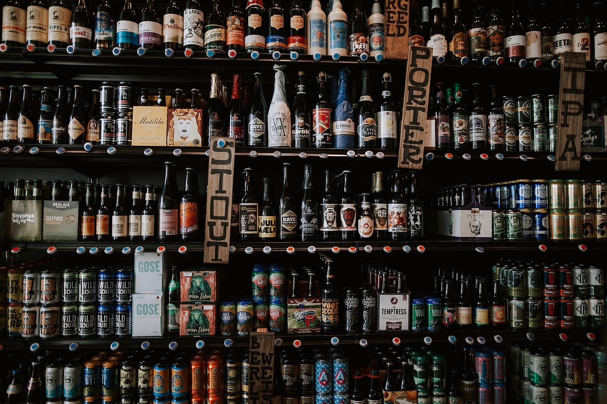 étagères remplies de bières artisanales rangées par catégories : IPA, Stout, etc.