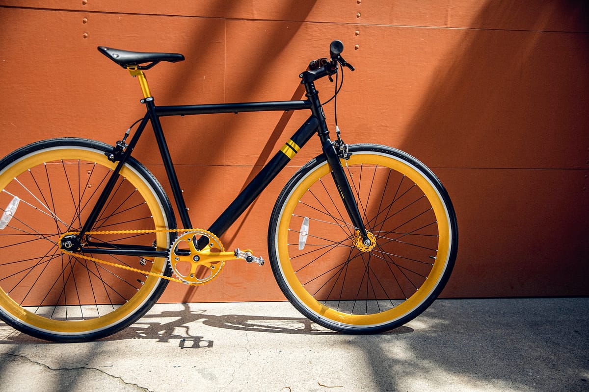 vélo de ville de couleur noir et orange adossé contre un mur