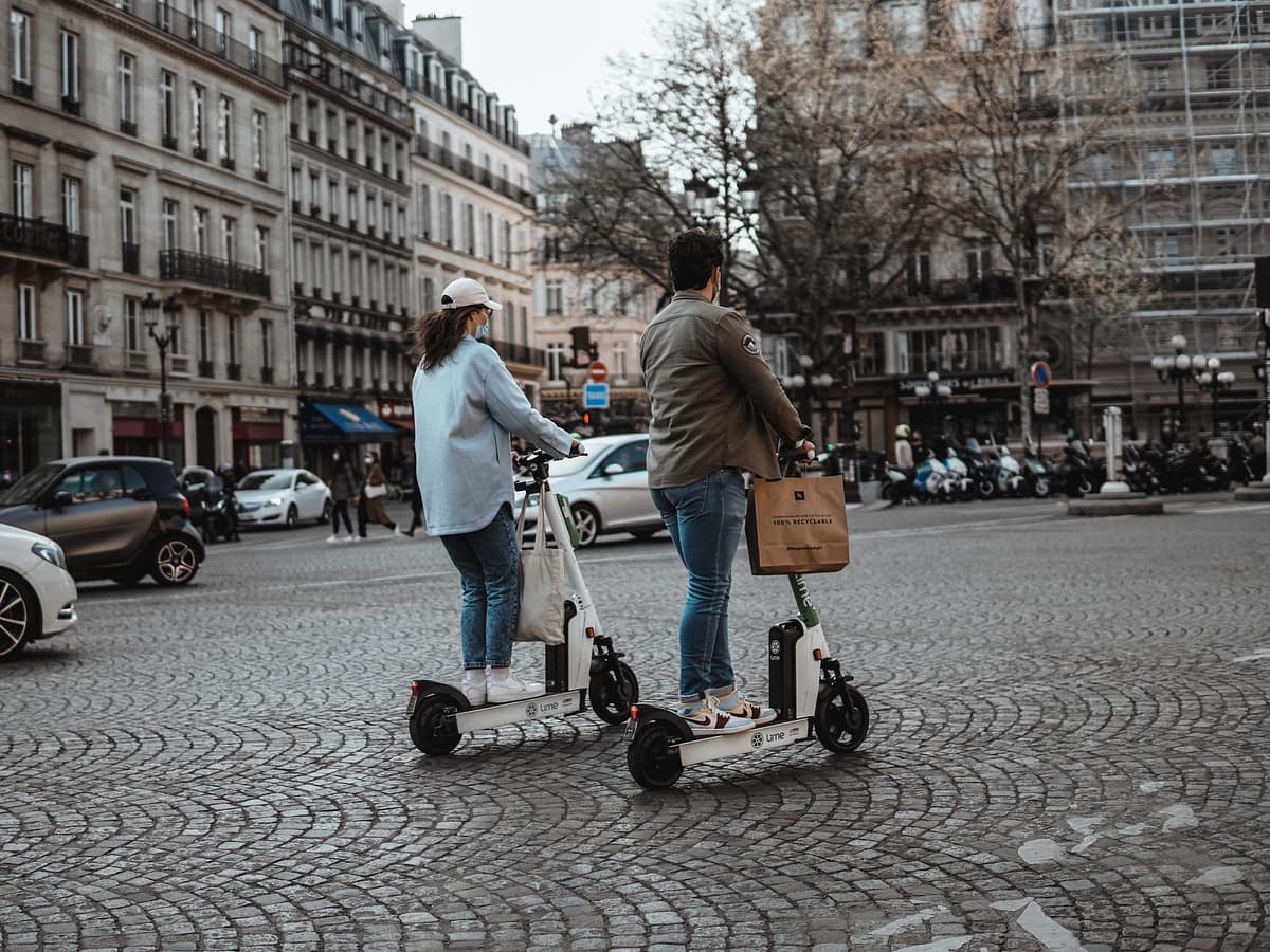 Deux touristes qui visitent Paris avec une trottinette électrique en libre service