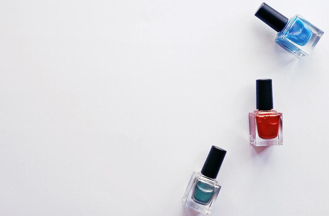 trois flacons de vernis à ongle sur fond blanc