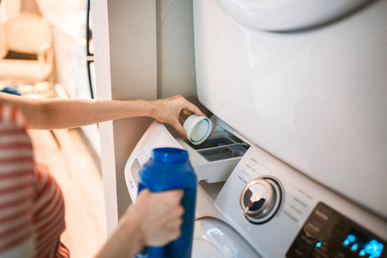 femme qui met de la lessive dans une machine à laver