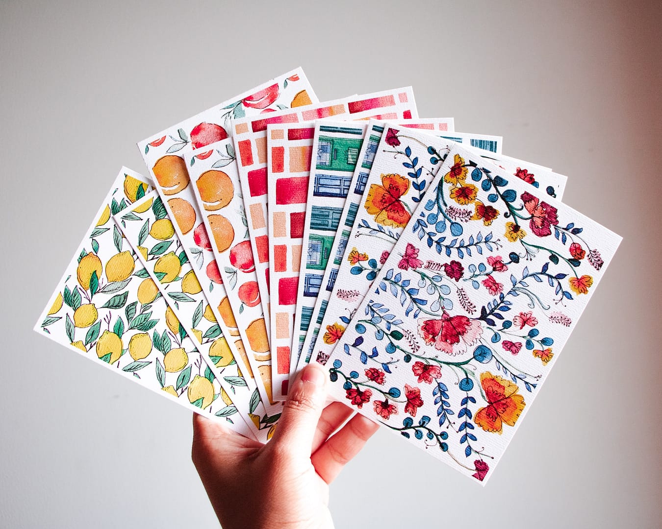 plusieurs cartes postales colorées dans une main
