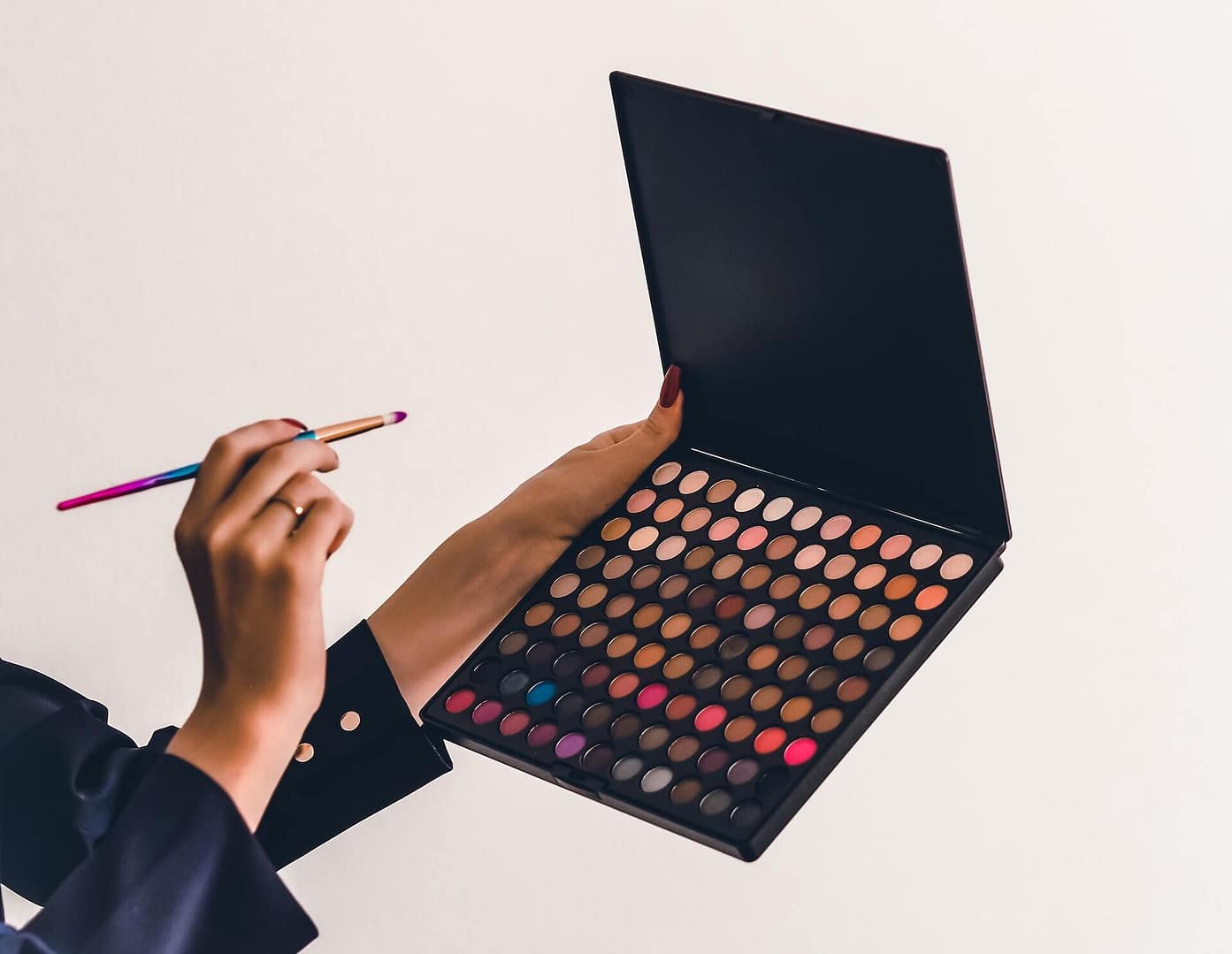 palette de fonds de teint de toutes les couleurs avec une main qui tient un pinceau