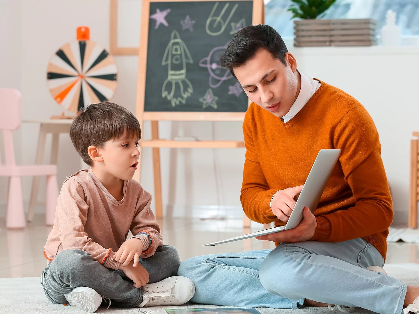 un orthophoniste assis avec un enfant dans son cabinet médical
