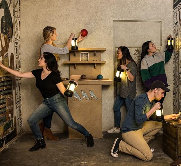 plusieurs participants à un escape game qui cherchent des indices