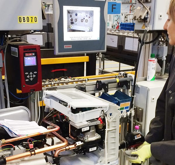 une salariée qui fabrique une pompe à chaleur dans une usine