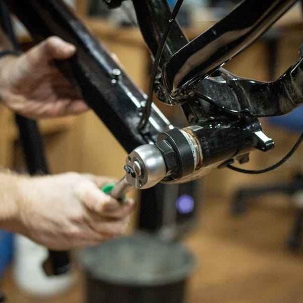 homme qui répare un vélo dans son atelier de réparation