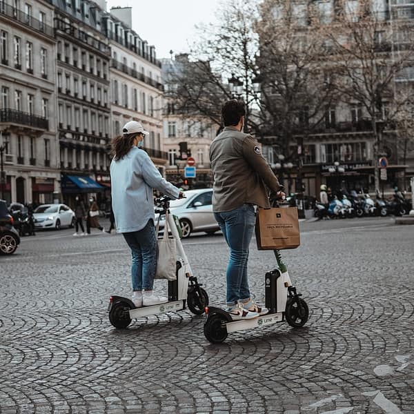 Deux touristes qui visitent Paris avec une trottinette électrique en libre service