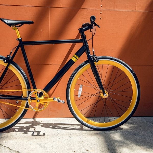 vélo de ville de couleur noir et orange adossé contre un mur