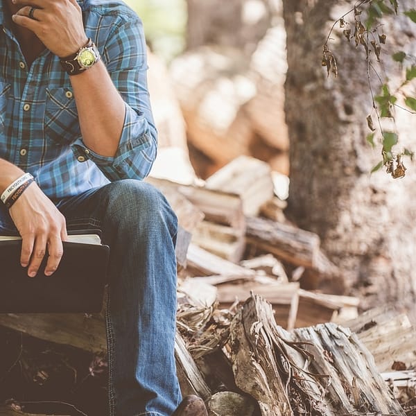 Homme assis sur un banc qui porte une montre et des bracelets