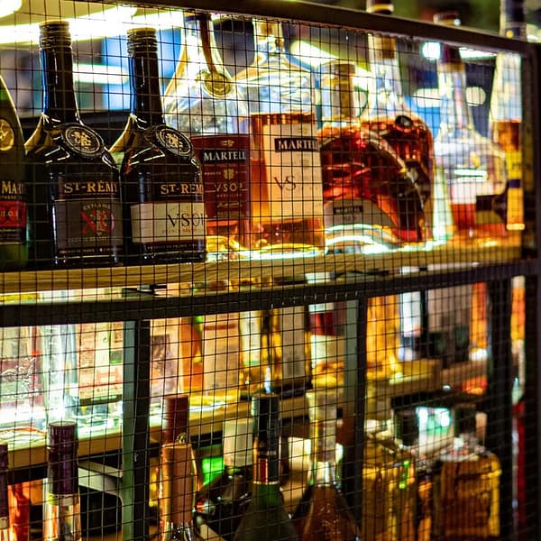 plusieurs bouteilles de Cognac de différentes marques sur une étagère dans un bar