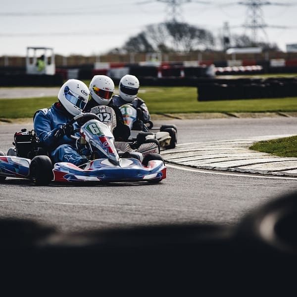 trois sportifs pratiquant le karting sur un circuit extérieur