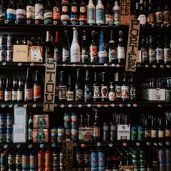 étagères remplies de bières artisanales rangées par catégories : IPA, Stout, etc.