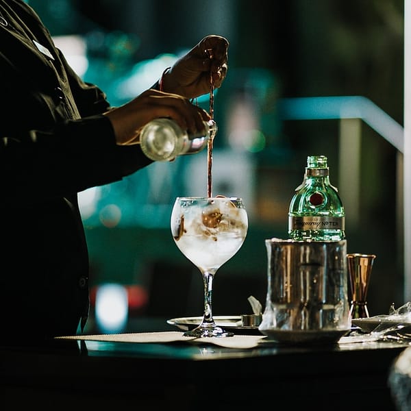 barman qui prépare un cocktail avec du gin