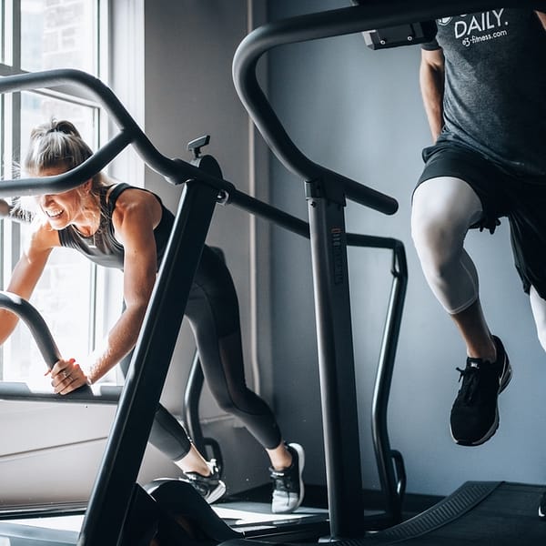 un homme et une femme sur des tapis de course dans une salle de sport