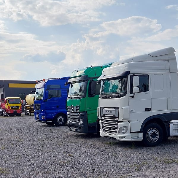 trois véhicules tracteurs de semi-remorque à l'arrêt près d'un site logistique