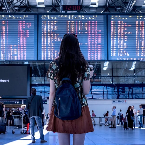 femme qui regarde le tableau de bords des vols dans un aéroport