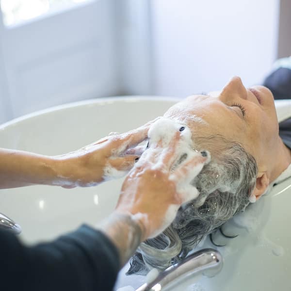 coiffeur qui fait un shampooing à une cliente