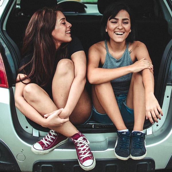 deux jeunes femmes en covoiturage assises dans le coffre d'une voiture