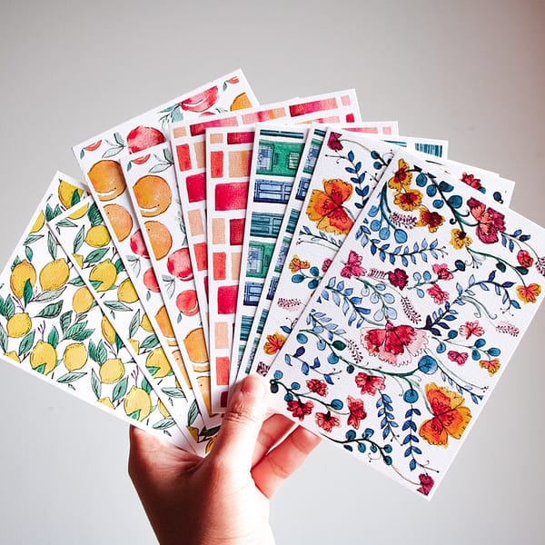 plusieurs cartes postales colorées dans une main