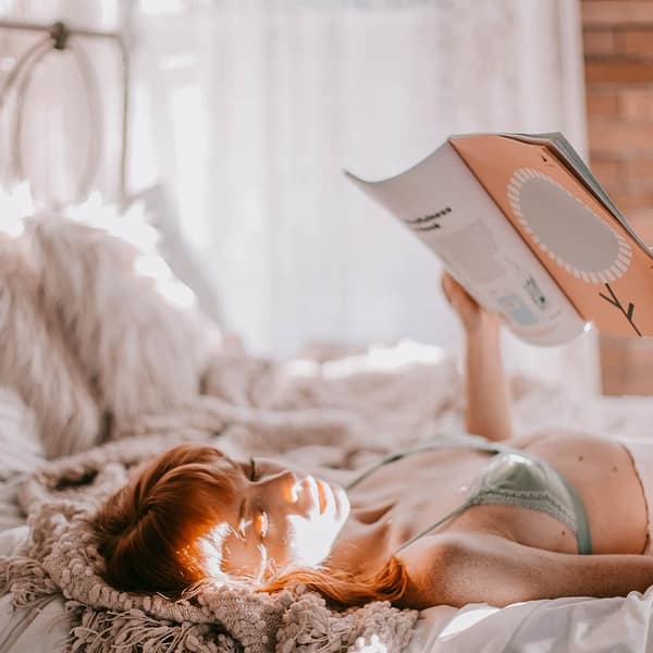 femme en lingerie qui lit un livre dans un lit