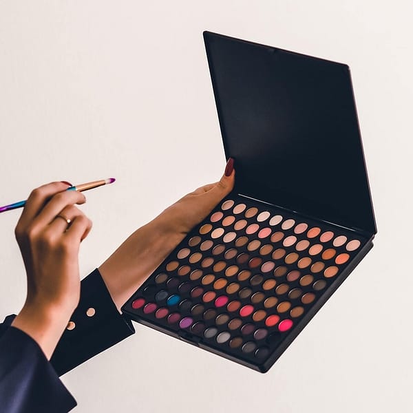 palette de fonds de teint de toutes les couleurs avec une main qui tient un pinceau