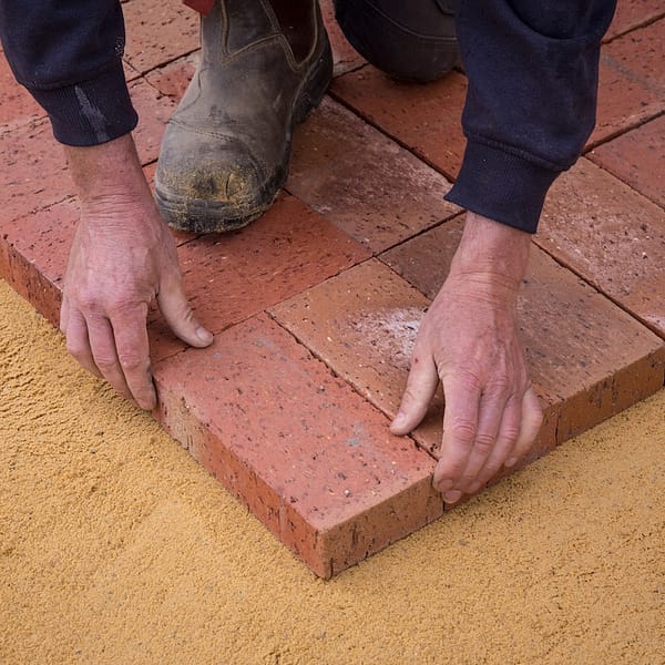 ouvrier qui place des briques sur le sol