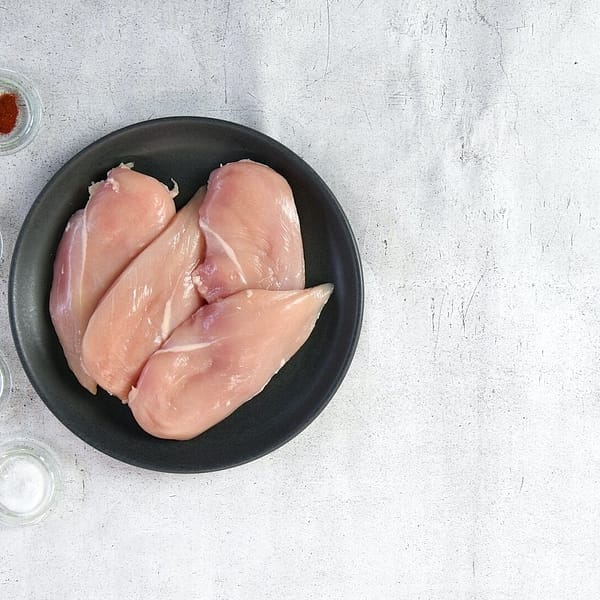 trois morceaux de poulet cru sur une assiette à côté de sauces